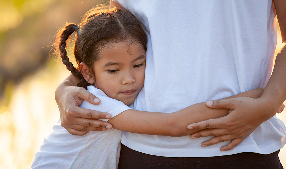 Little girl, sad, holding parent's waist, giving hug.