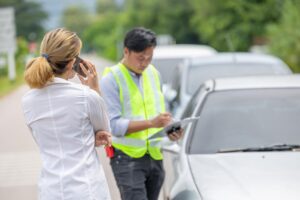Women car problem crash talking phone call for help insurance man officer agent roadside damage assessment report.